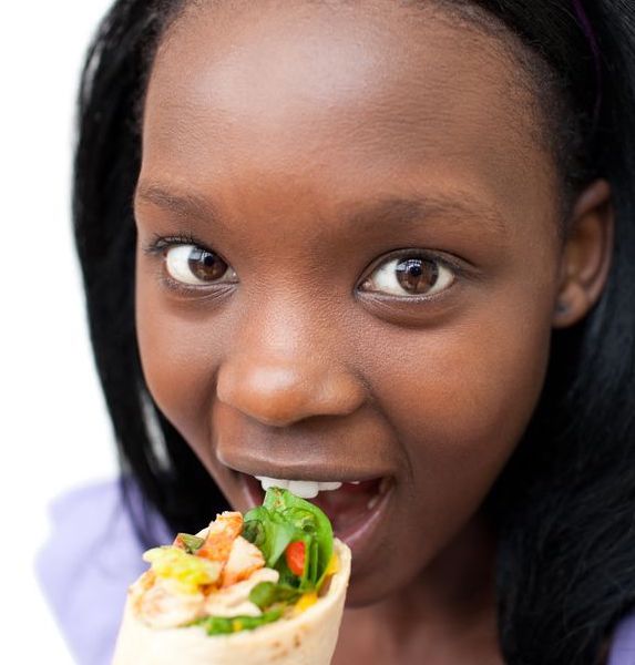10240514 young woman eating a wrap